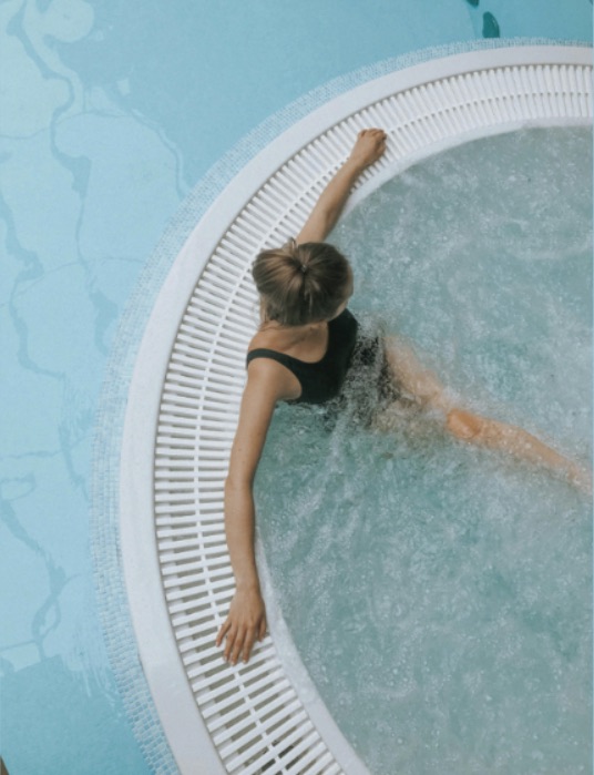 Person relaxing in a hot tub with turquoise water